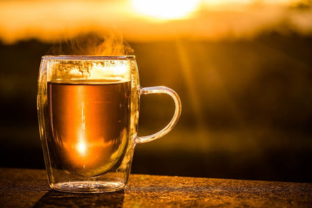 steaming hot glass of tea at sunrise