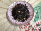 Black tea on a pink plate  showing small dried fruit pieces